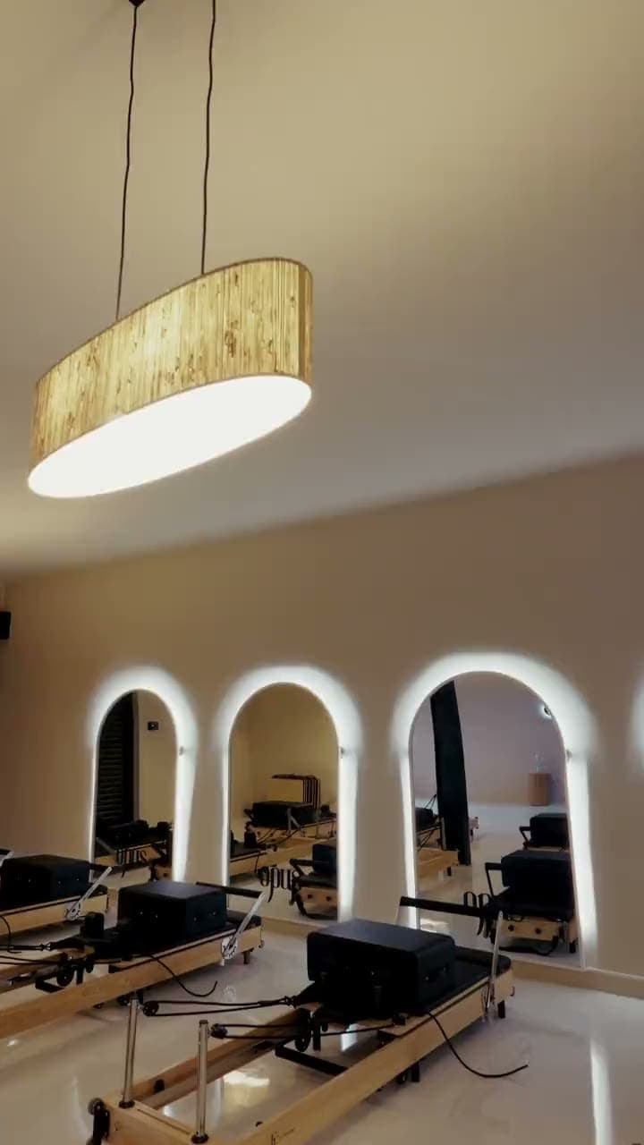 The Reformer studio at Opus: oak reformers under backlit arched mirrors