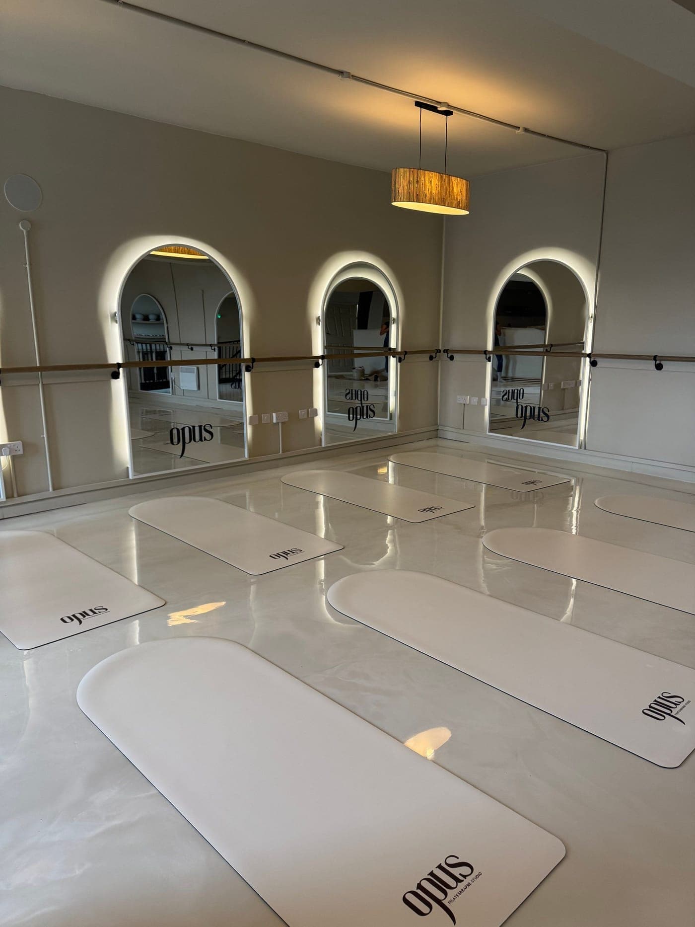 The Mat studio set for class, opus mats laid out beneath the lit arched mirrors