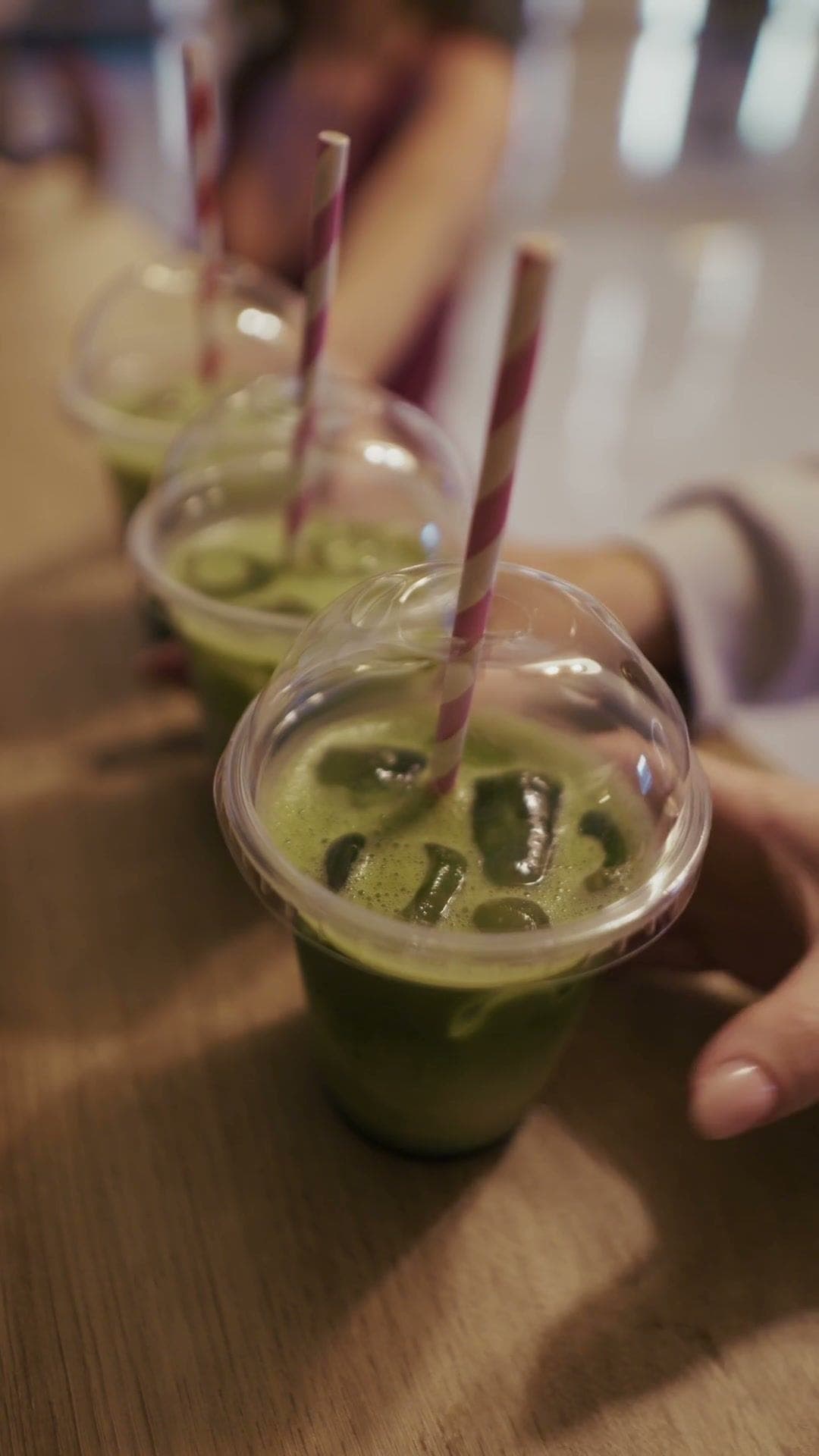 Green smoothies with striped straws on the counter