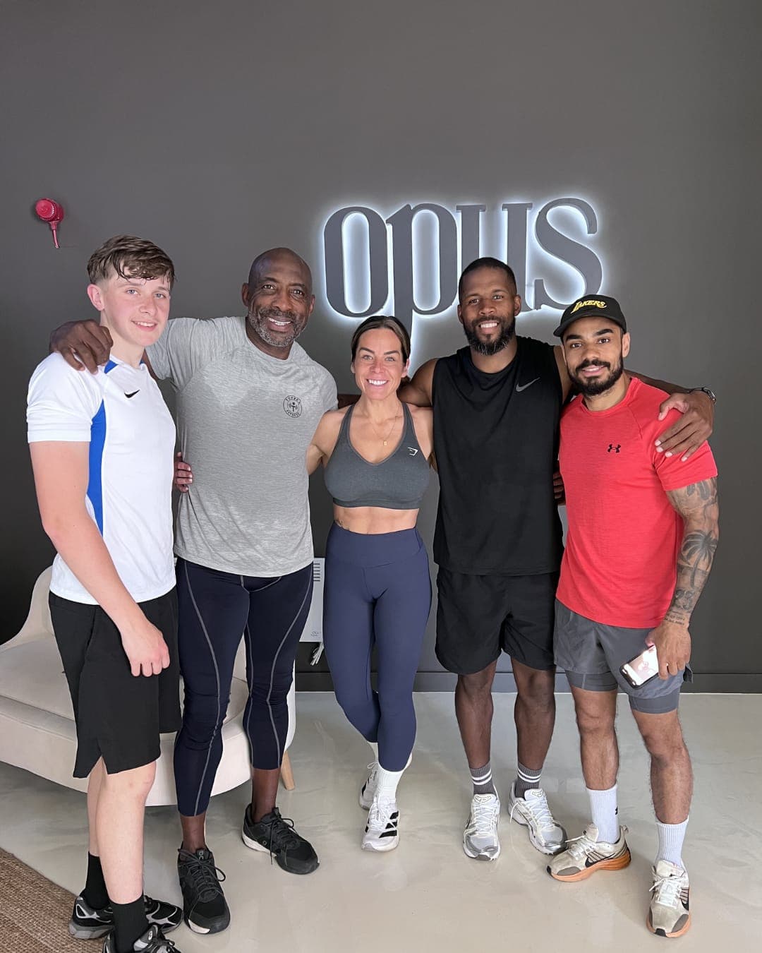 Johnny Nelson MBE with Opus members and the team under the lit opus sign