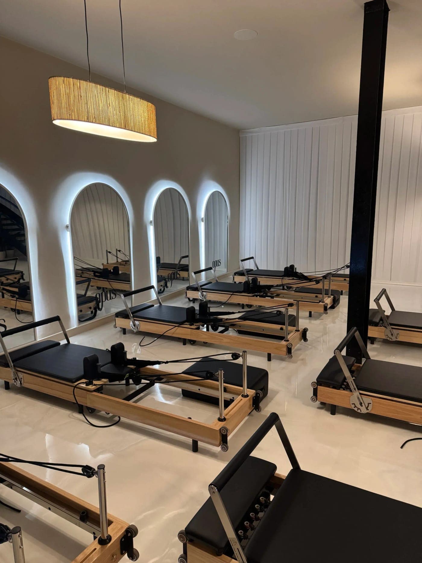 The empty Reformer studio at Opus, oak reformers lined up beneath the backlit arched mirrors
